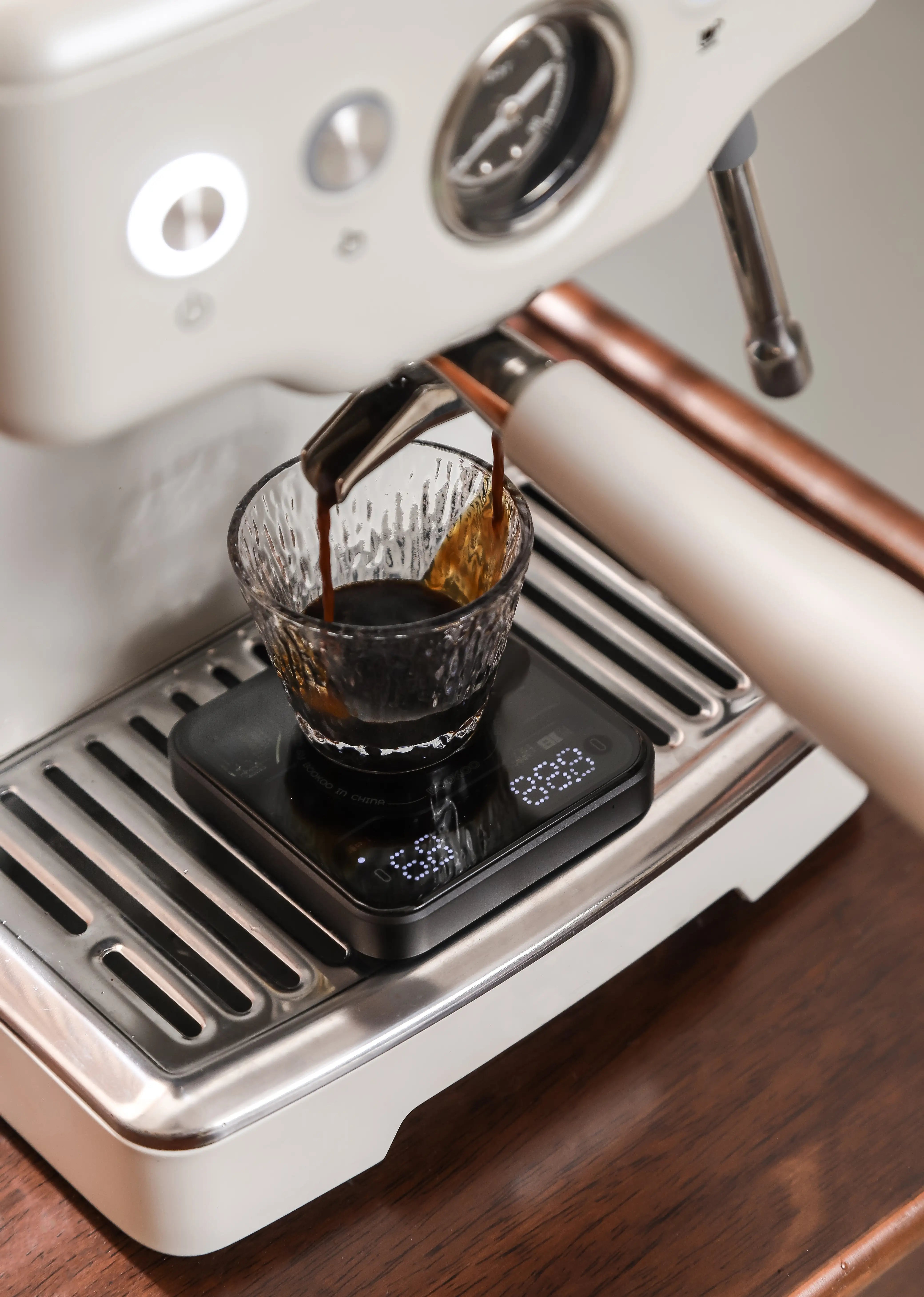 Aktionsbild der BOOKOO THEMIS Mini, steht auf Espressomaschine, die grade einen Espresso Shot ausführt
